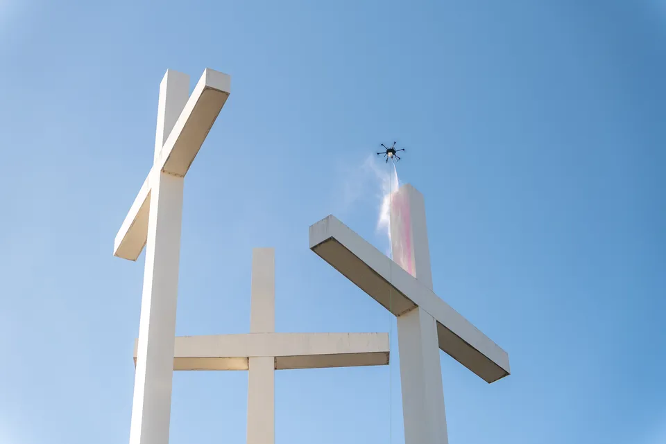 Lucid Bots Sherpa cleaning drone applying solution to tall white architectural elements