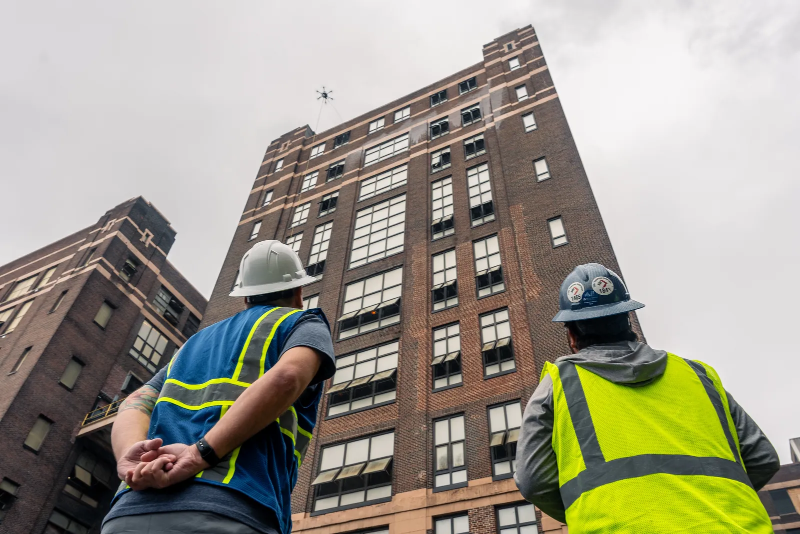 Lucid Bots Sherpa cleaning drone operating beside a large industrial-style building exterior